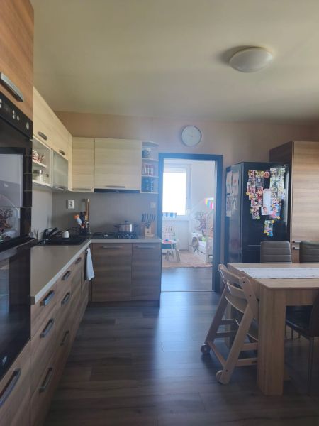 A kitchen in a 3-room apartment with a wood-patterned floor and a dining table.