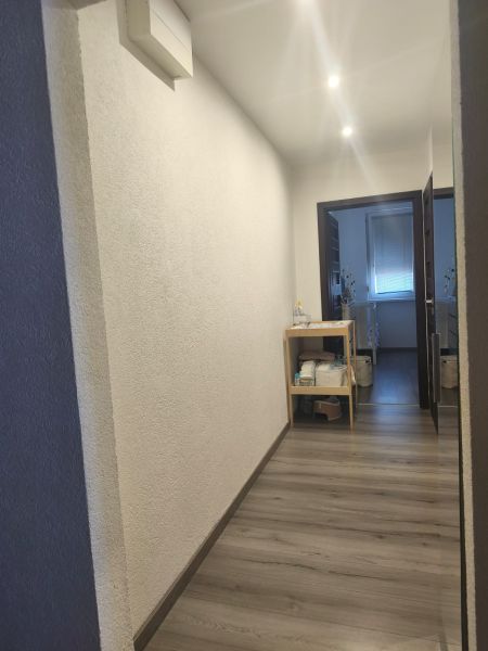 A hallway in a 3-room apartment with a wooden decor floor and lighting.