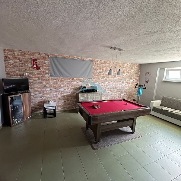 Game room in a family house with a pool table and a brick wall.