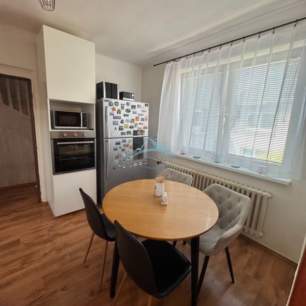 A kitchen in a family house with a wooden decor floor, a round table, and appliances.