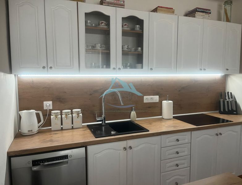 A kitchen in a family house with white cabinets and a wooden decor countertop.