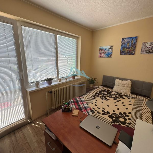 A room in a family house with a bed, a table, flowers, and decorative paintings.