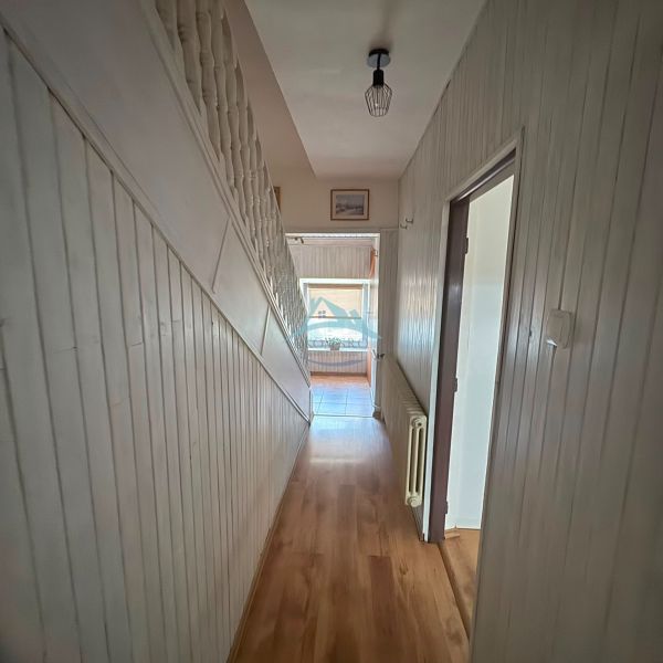 A hallway with a wooden decor floor in a family house with white walls and railing.