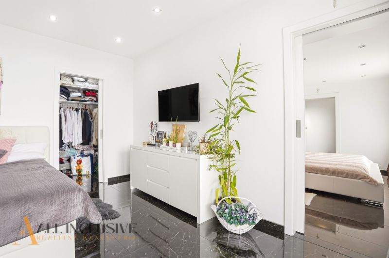 A bedroom in a family house with a dark floor, a TV on the wall, and a wardrobe.