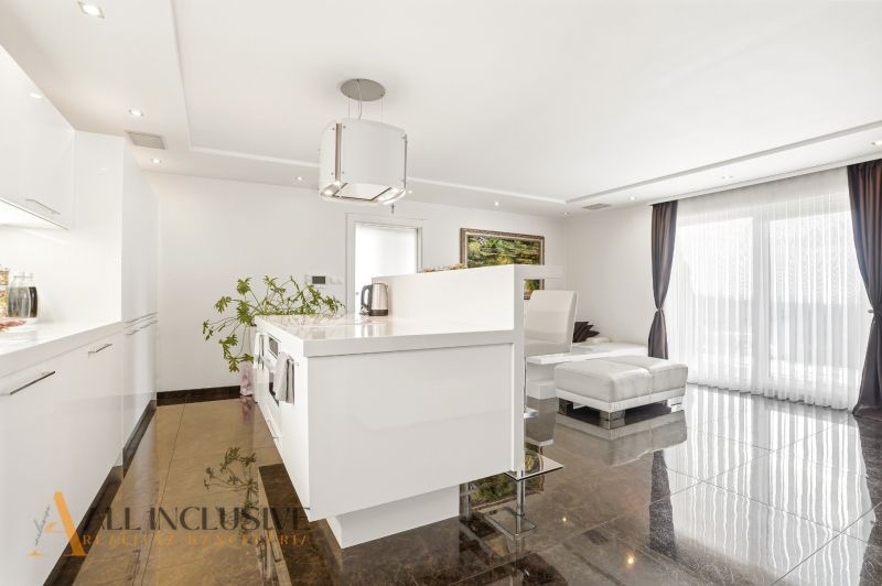 A kitchen in a family house with a shiny floor and a large window.
