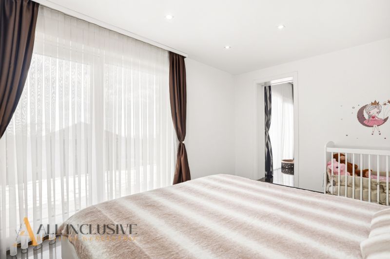Bedroom with a baby crib, wall decoration, and a large window in a family house.