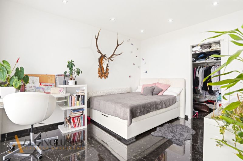 A bedroom in a family house with a desk, storage space, and wall decoration.