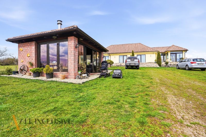 A family house in Kopanice in Krupina surrounded by a green lawn and cars in the parking lot.