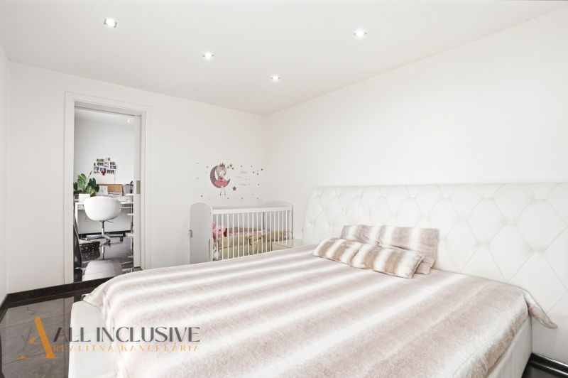 A bedroom in a family house with a bed, a baby crib, and a work corner.