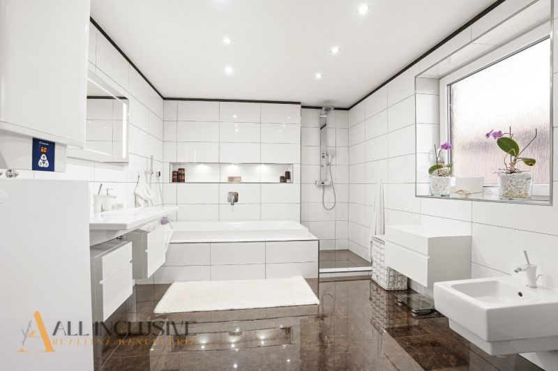 White bathroom with a bathtub and shower in a family house.