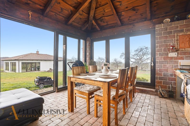 Dining room in a family house with brick walls, a table, and a view of the garden.