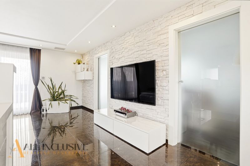 Living room with a TV on the wall and a wooden decor floor in a family house.