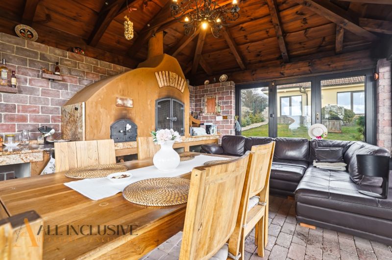 A kitchen corner in a family house with a stove, wooden table, brick wall, and seating area.