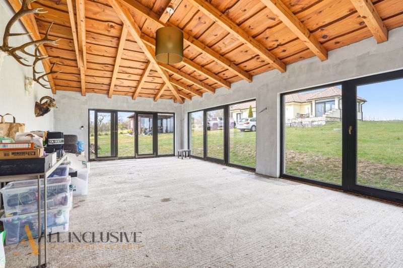A glazed space in a family house with a wooden ceiling and a view of the garden.
