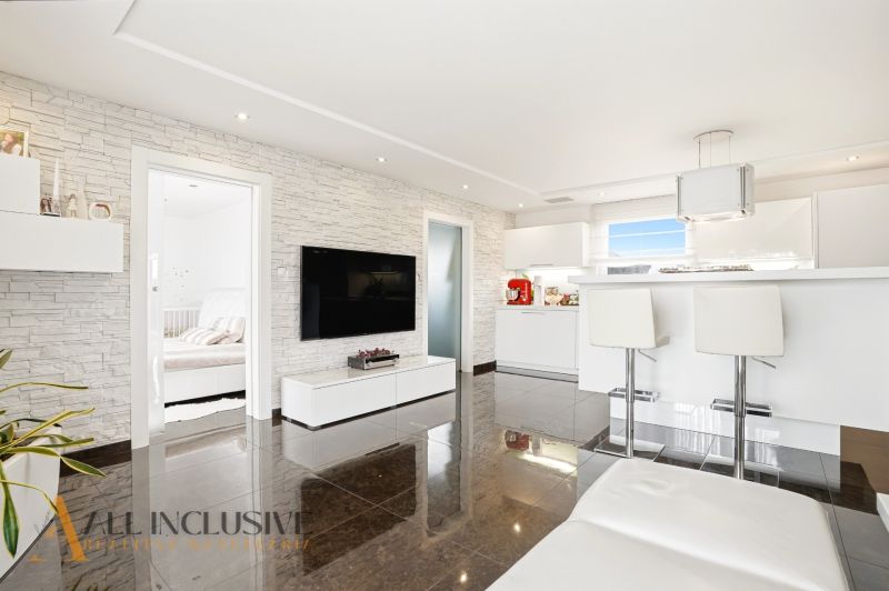 Living room in a family house with white furniture and a kitchenette.