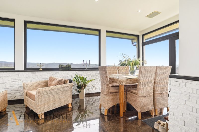 A spacious interior of a family house with rattan furniture and large windows.