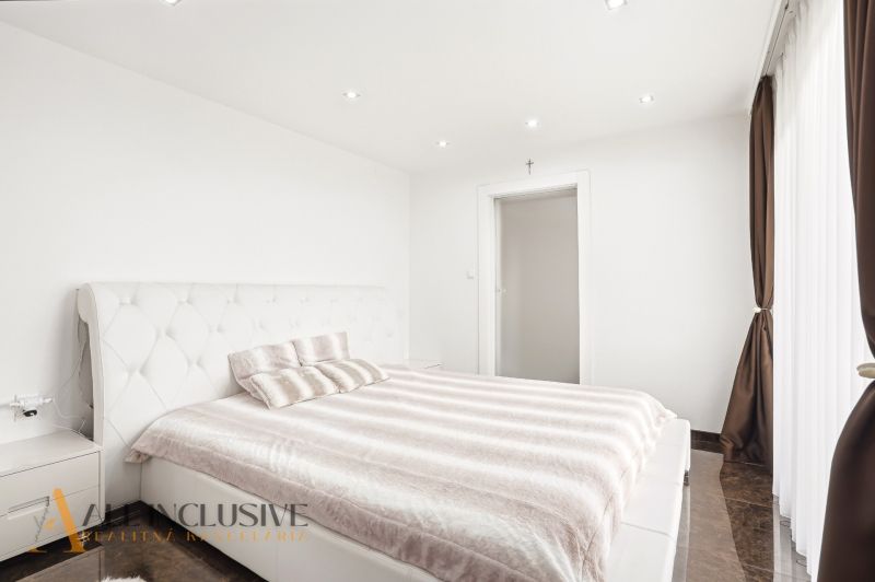 A bright bedroom in a family house with white furniture and a large window.