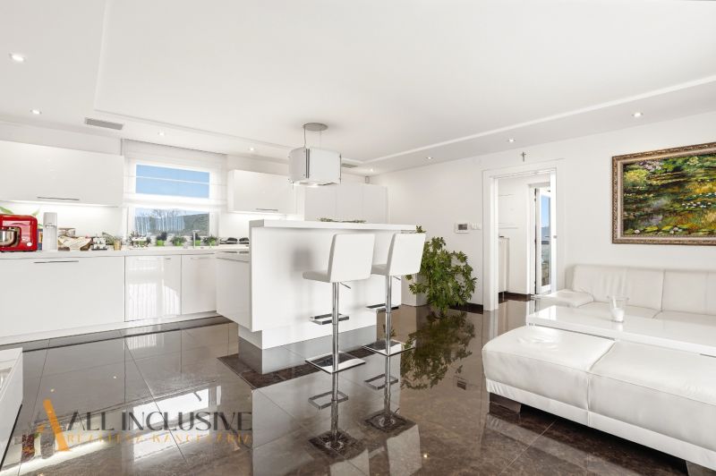 A bright kitchen in a family house with white furniture and glossy tiles.