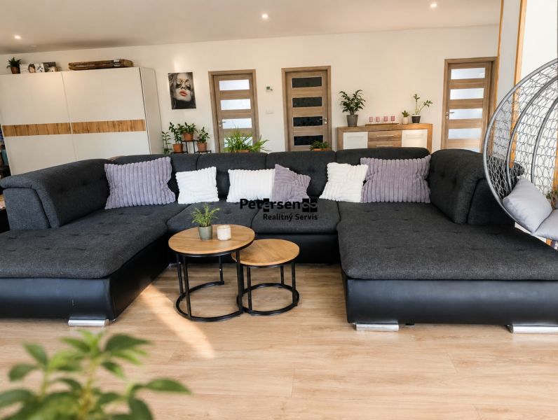Living room with a large sofa, tables, and a wooden decor floor in a 3-room apartment.
