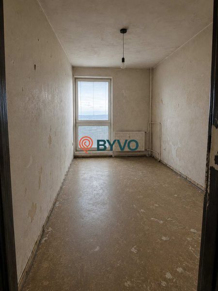 Empty room in a studio apartment with flooring and a simple light.
