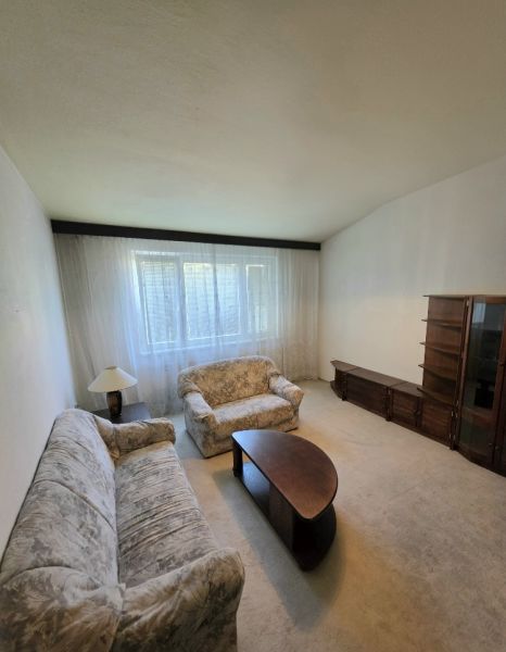 Living room in a 3-room apartment with a sofa, an armchair, and dark furniture.