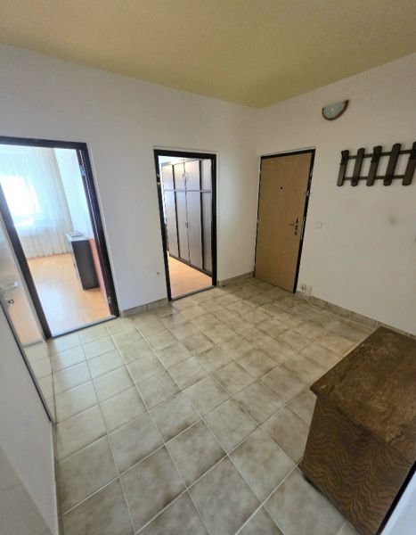 A hallway with light tiles and a wooden shoe cabinet in a 3-room apartment.
