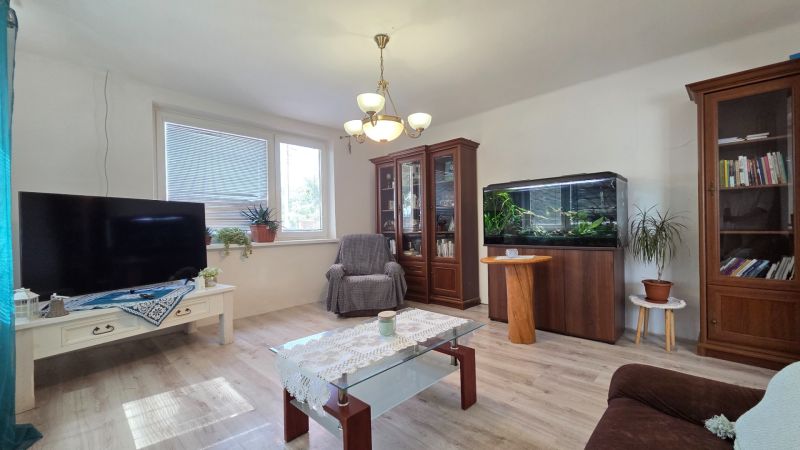 Living room in a family house with an aquarium, television, and wooden decor flooring.