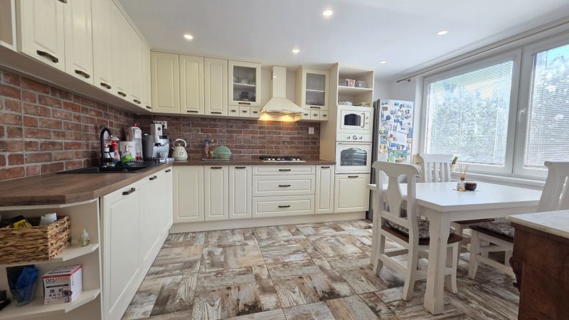A kitchen with brick cladding and a wooden decor floor in a family house.