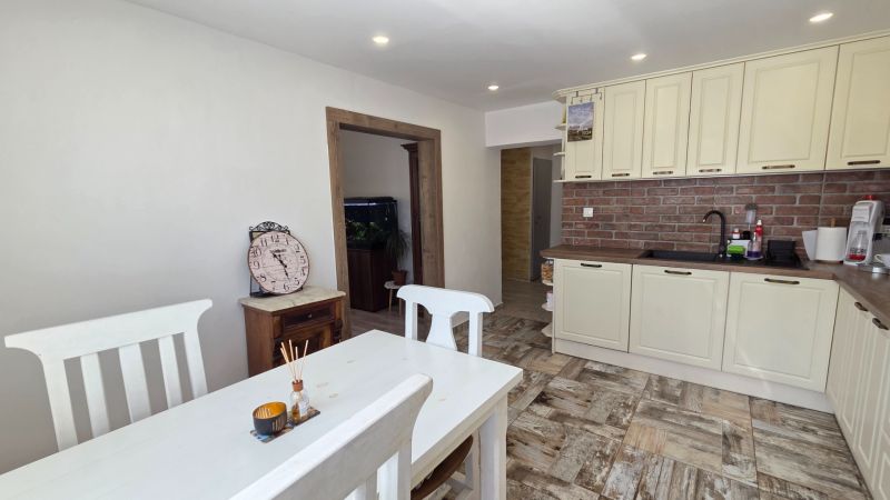 A family house kitchen with a wooden decor floor and brick cladding.