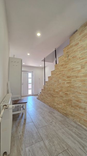 Entrance hall of a family house with a staircase featuring a stone design and a floor with a wood design.