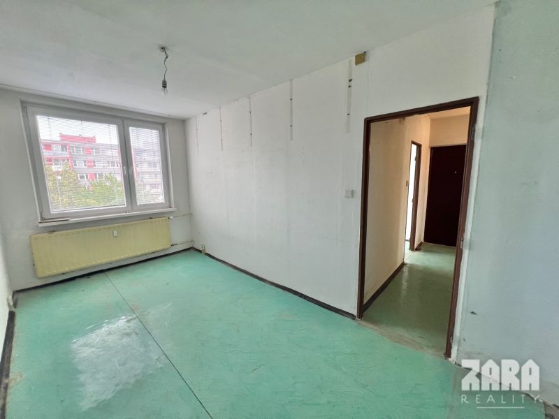 A room with windows, a green floor, white walls in a three-room apartment.
