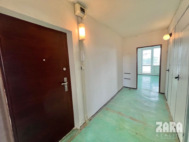 A hallway with an entrance door and a passage to a room in a 3-room apartment.