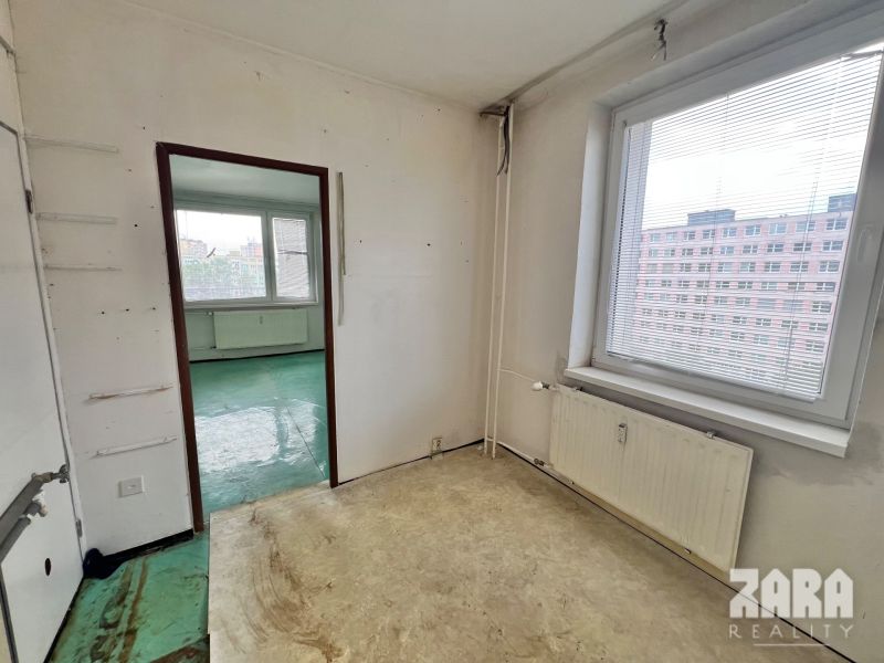 A room in a 3-room apartment with a view of a block of flats and a window with blinds.
