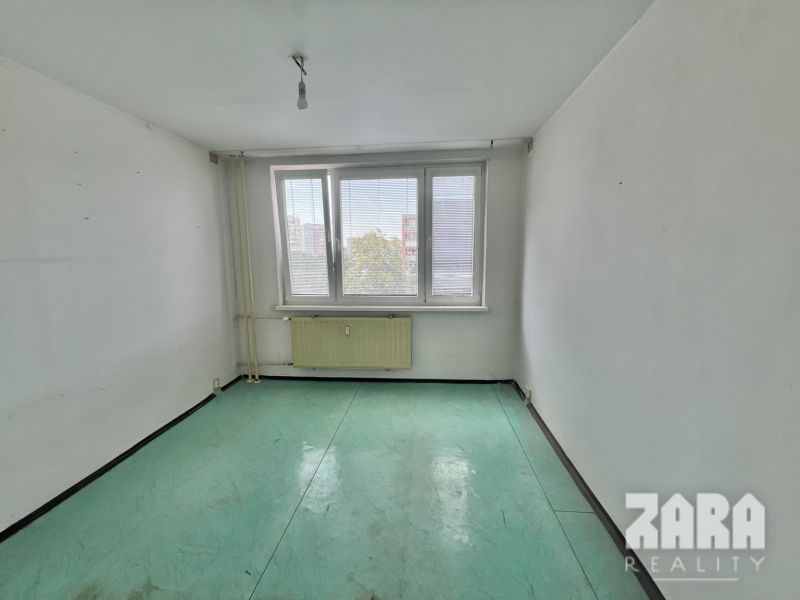 A room with white walls and a green floor in a 3-room apartment.