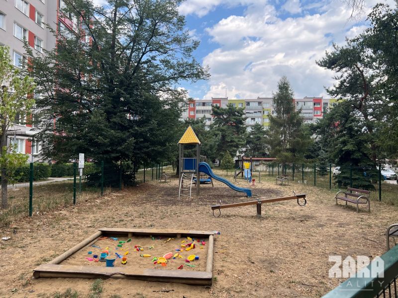 A children's playground with climbing frames and a sandbox near a 3-room apartment on Družicová Street.
