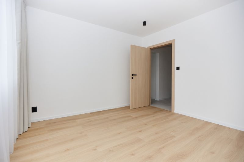 A room with a wooden decor floor and a door in a 3-room apartment.
