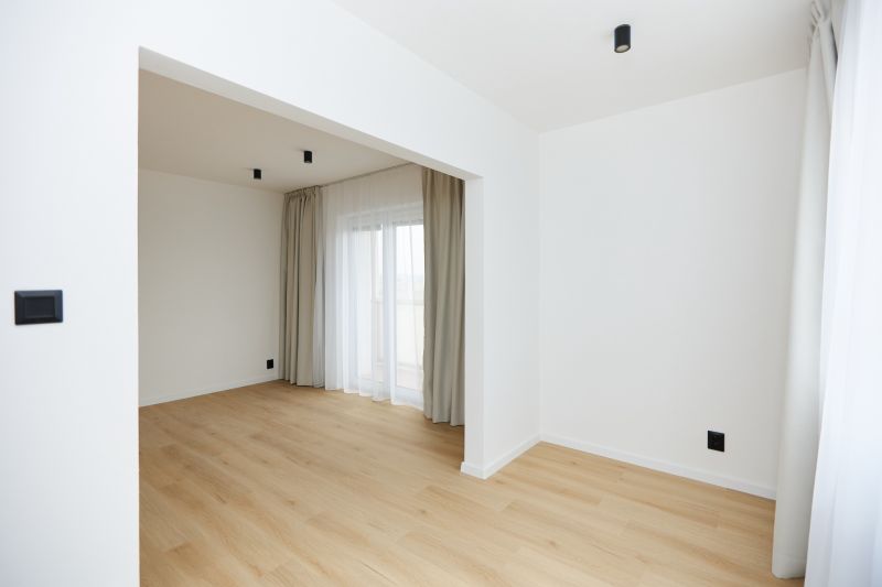 A room in a 3-room apartment with a wooden decor floor, curtains, and a French window.