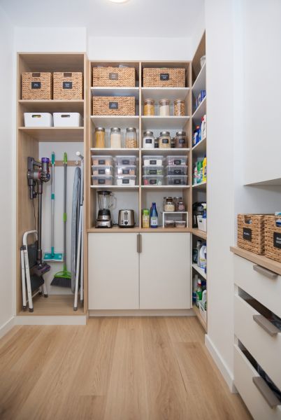 A pantry organized in a 3-room apartment with shelves and a floor with a wooden decor.