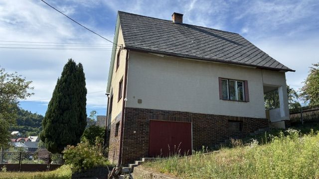 A family house in Lednice with a wooden decor and a sloped roof, surrounded by greenery.