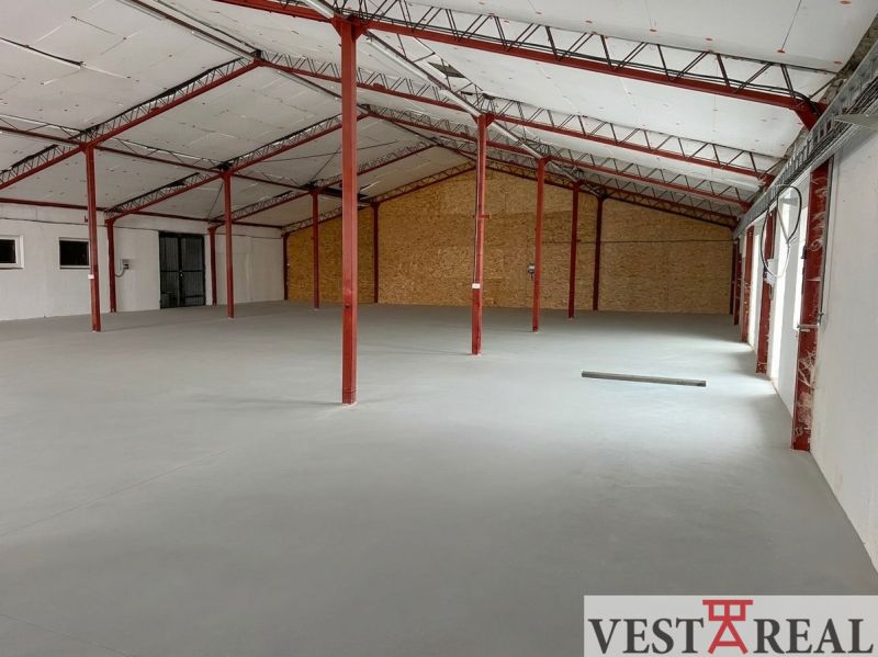 A spacious interior of a hall with iron beams and a white ceiling.