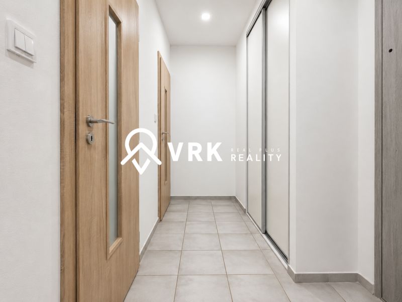 A hallway with tiles in a studio apartment, wooden doors, and white wardrobes.