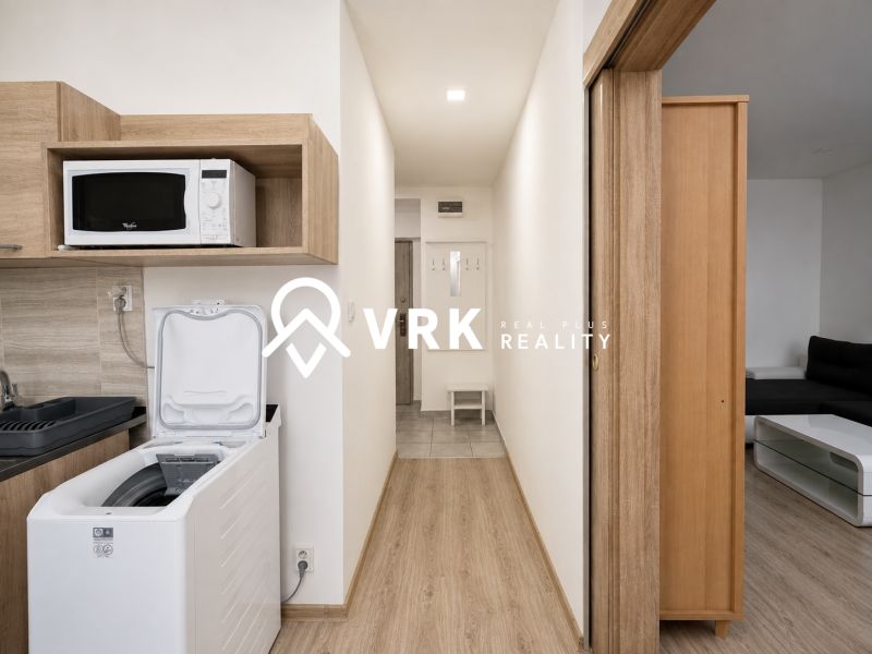 Cozy interior of a studio apartment with a kitchenette and a microwave, wooden decor flooring.