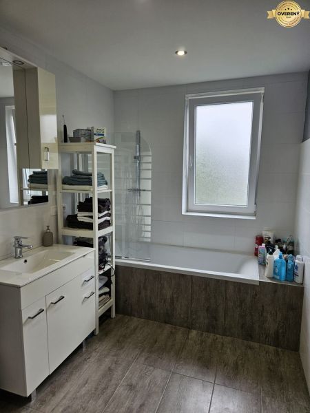 Bathroom in a 4-room apartment with a bathtub, a towel rack, and a wooden decor floor.