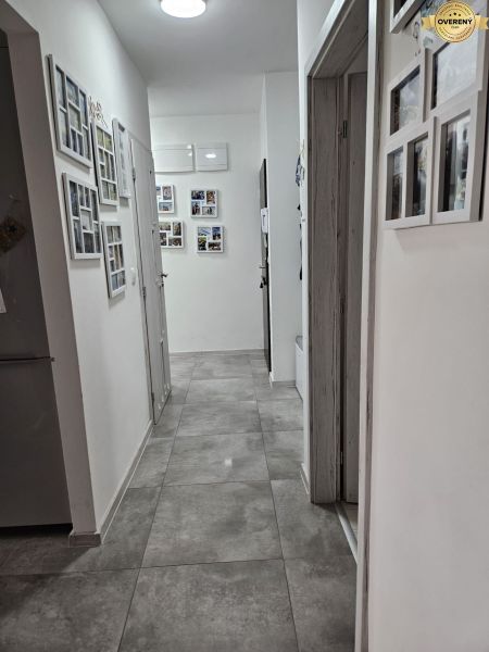 A hallway with gray tiles and photo frames in a 4-room apartment.