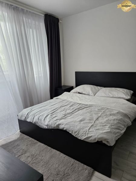 A bedroom with a bed and curtains in a 4-room apartment with a wooden decor floor.