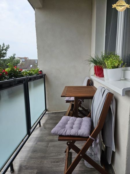 Balcony of a 4-room apartment with wooden furniture and plants, floor with wooden decor.