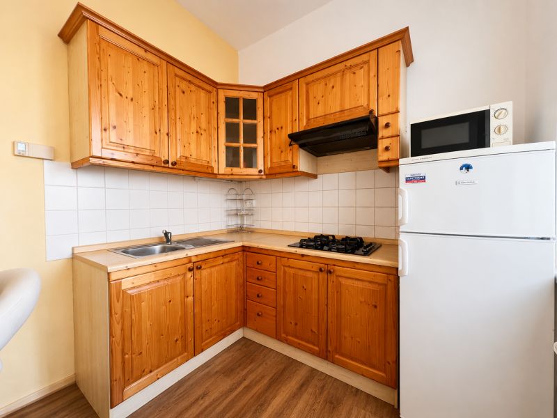 A kitchen in a studio apartment with wooden cabinets and a wood-patterned floor.