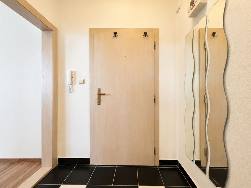 Entrance hall in a one-room apartment with a black floor and a wavy mirror.