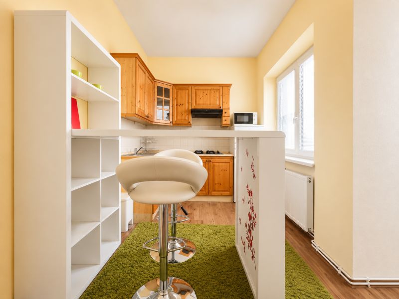 A kitchen with wooden decor in a studio apartment, a bar counter, and a green carpet.