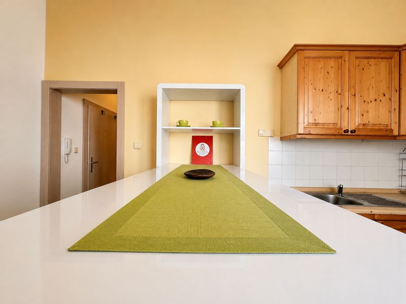 A kitchen unit with wooden cabinets and green placemats in a studio apartment.